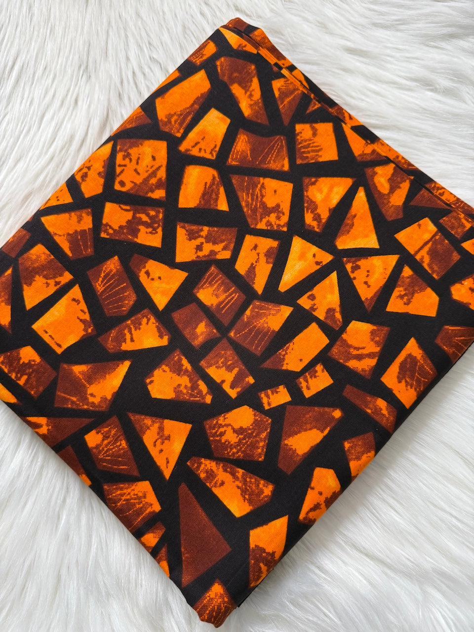 Patterned fabric with orange and brown geometric design on a white surface