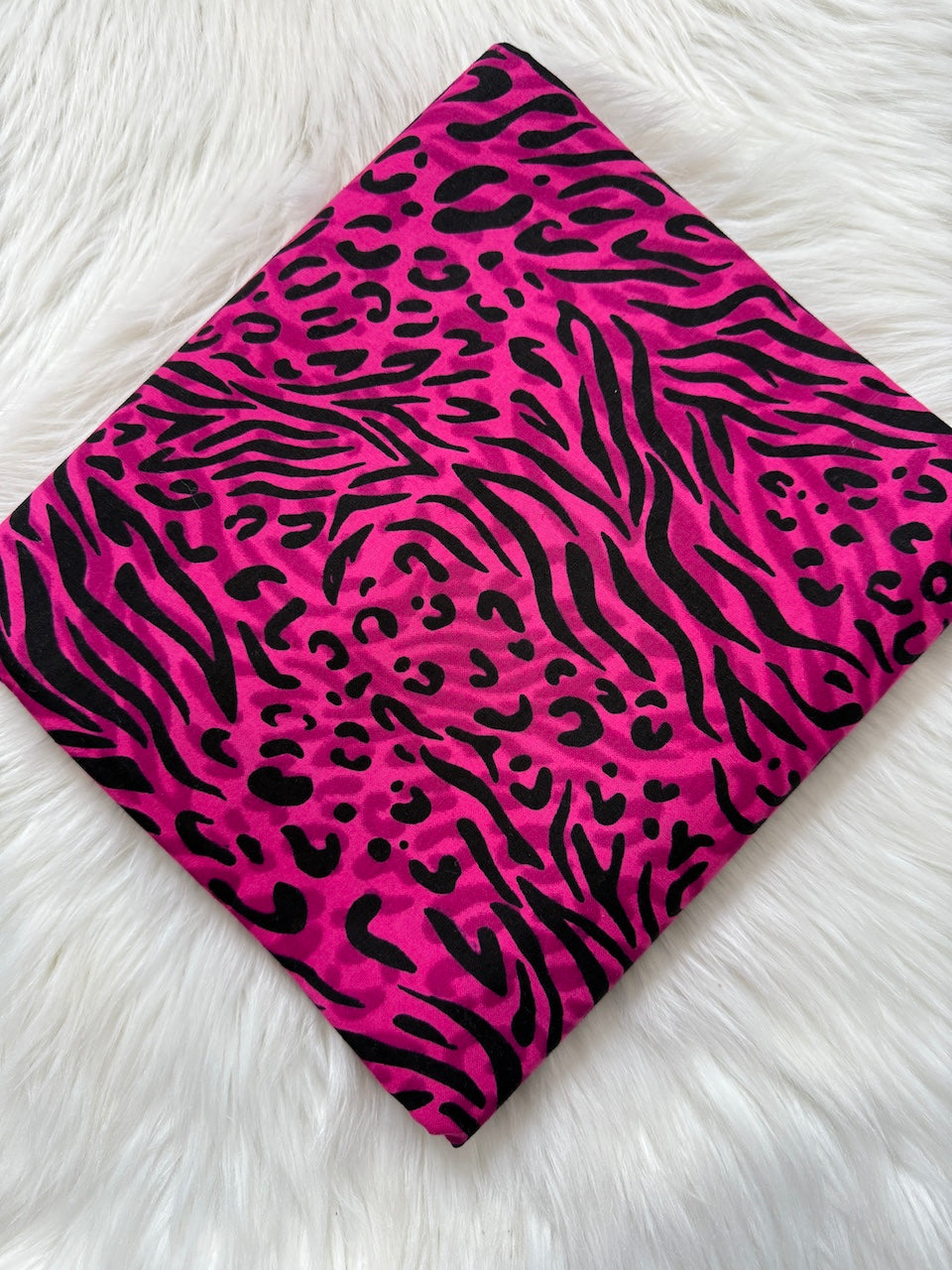 Pink and black animal print fabric on a white fur background