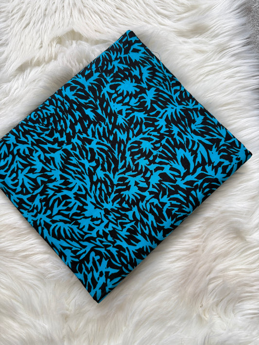 Folded fabric with blue and black pattern on a white fluffy surface