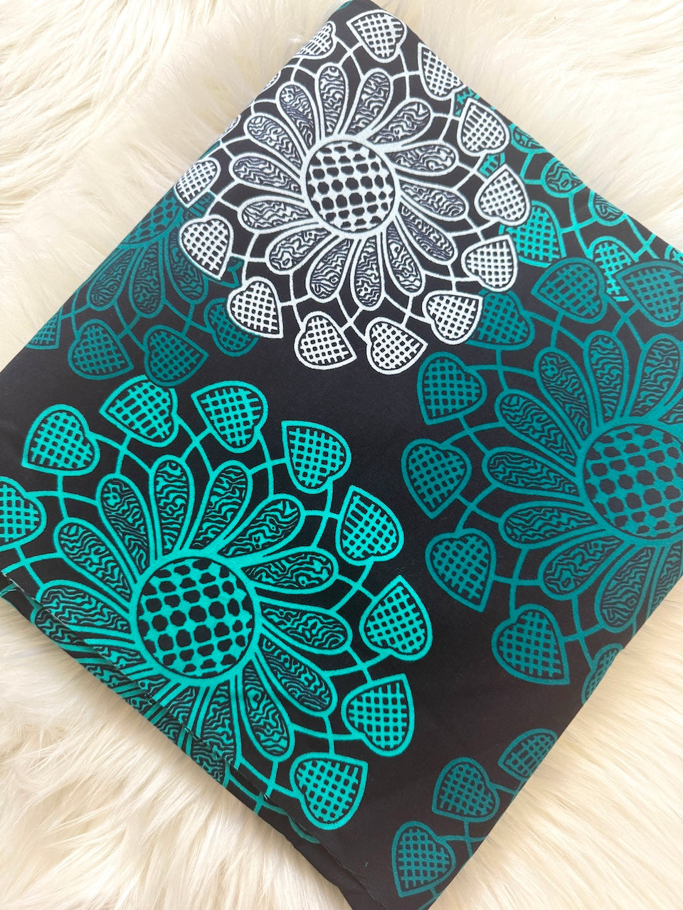 Black notebook with teal and white floral patterns on a light wooden surface