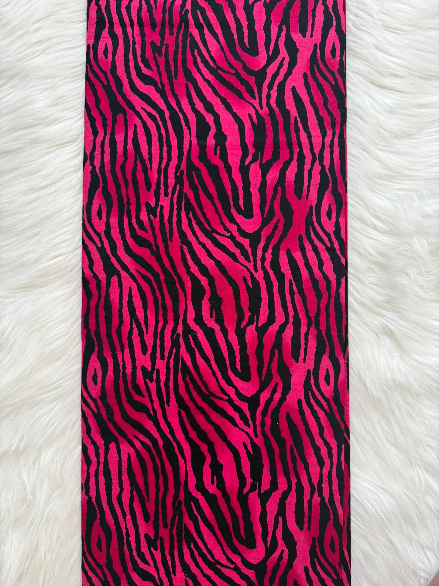 Strip of pink and black zebra pattern fabric on a white fur background