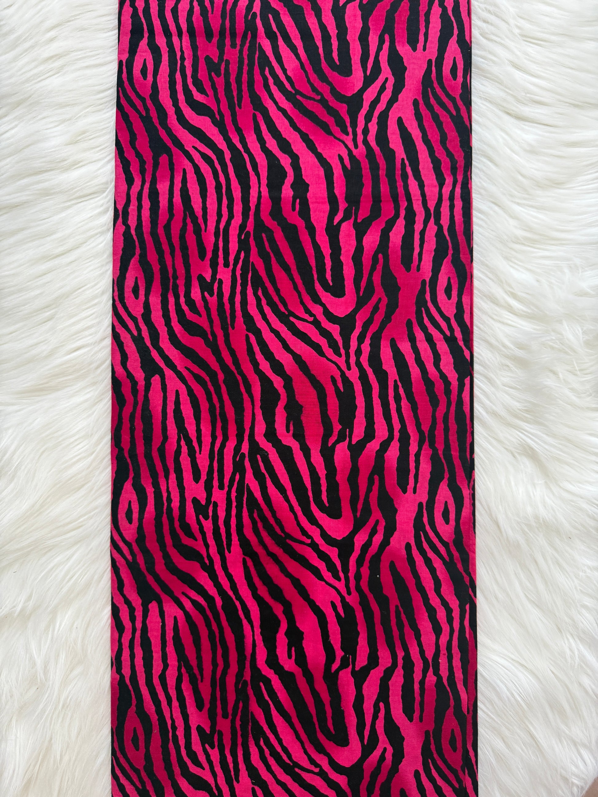 Strip of pink and black zebra pattern fabric on a white fur background
