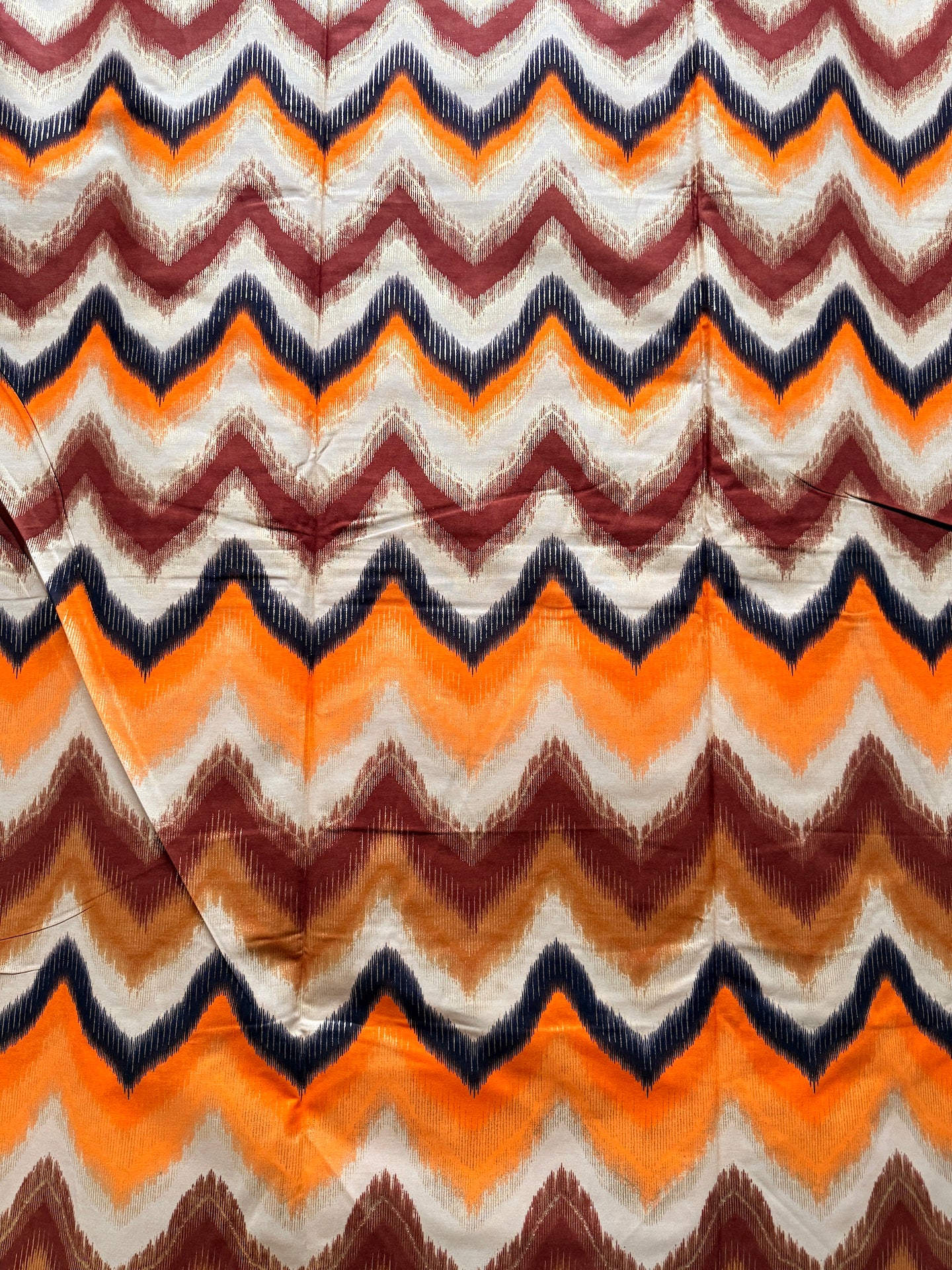 Fabric with zigzag pattern in orange, brown, and blue.