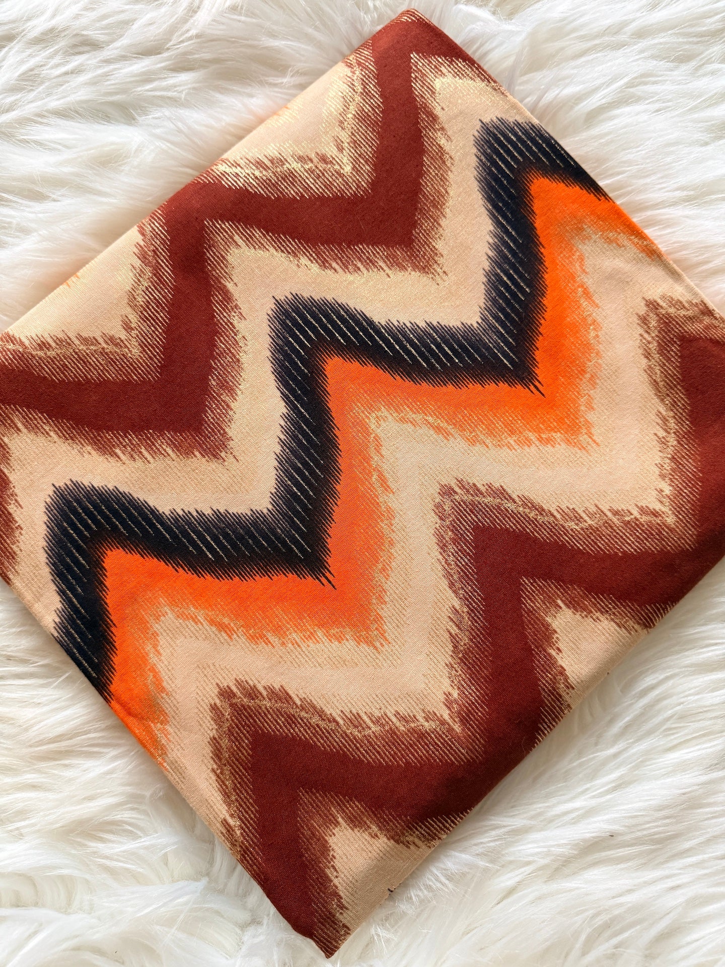 Hexagonal fabric pillow with zigzag pattern on a white fluffy surface