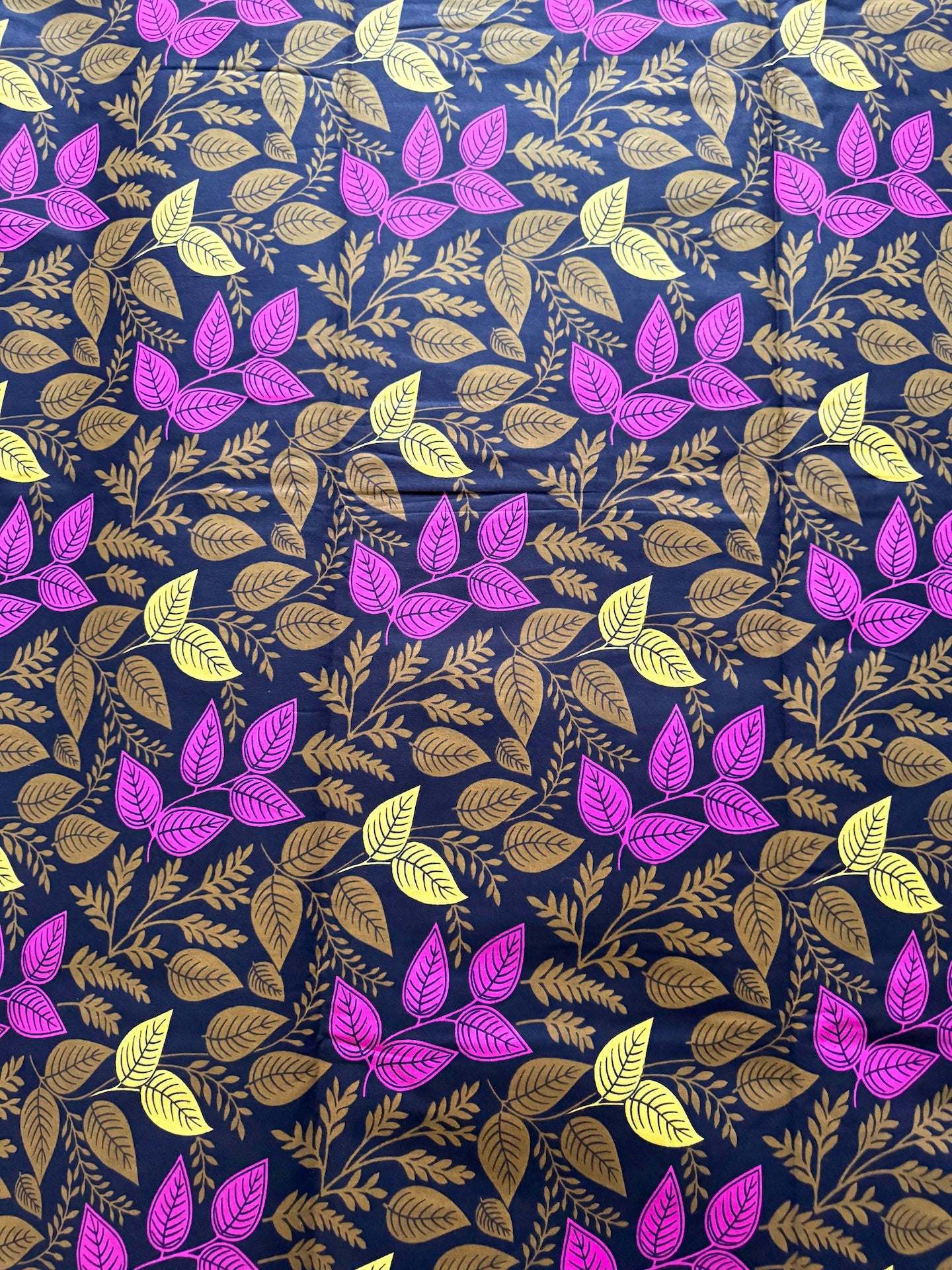 Patterned fabric with purple, yellow, and green leaves on a dark blue background