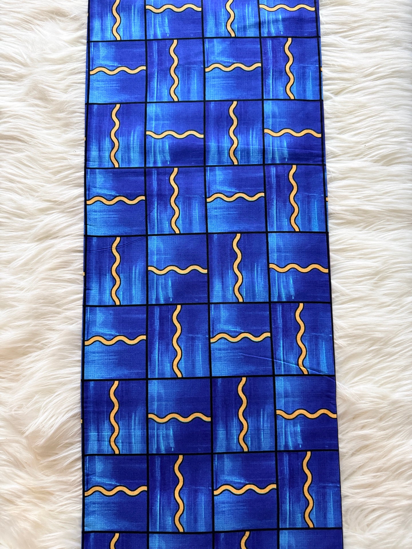 Blue fabric with gold patterns on a white fluffy surface