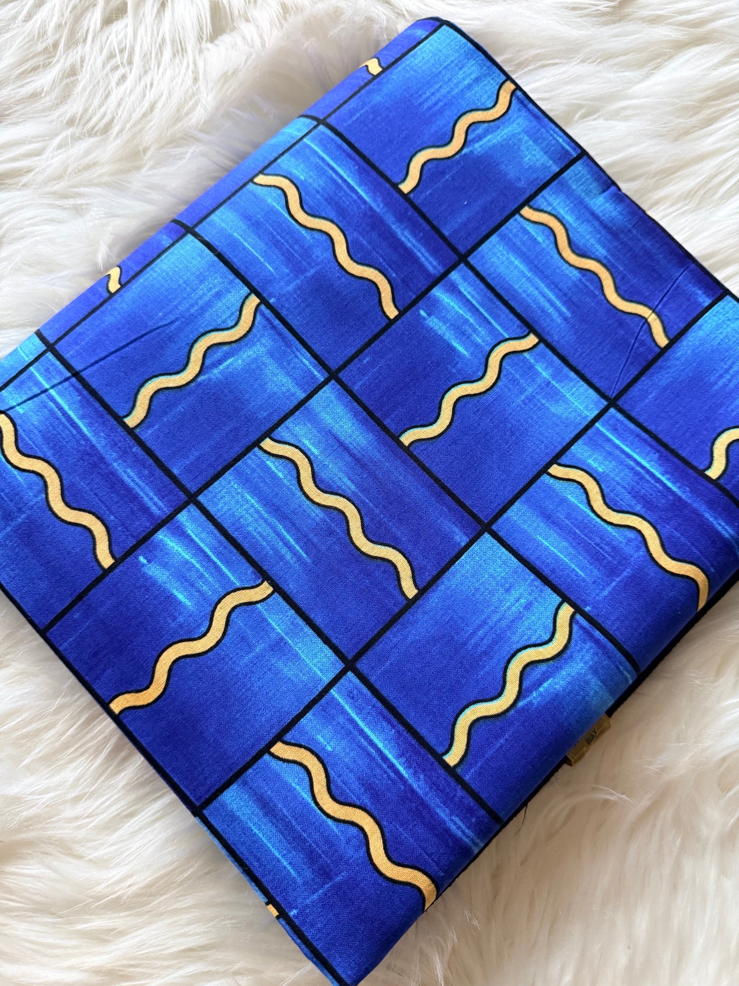 Blue rectangular object with wavy yellow lines on a white fluffy surface