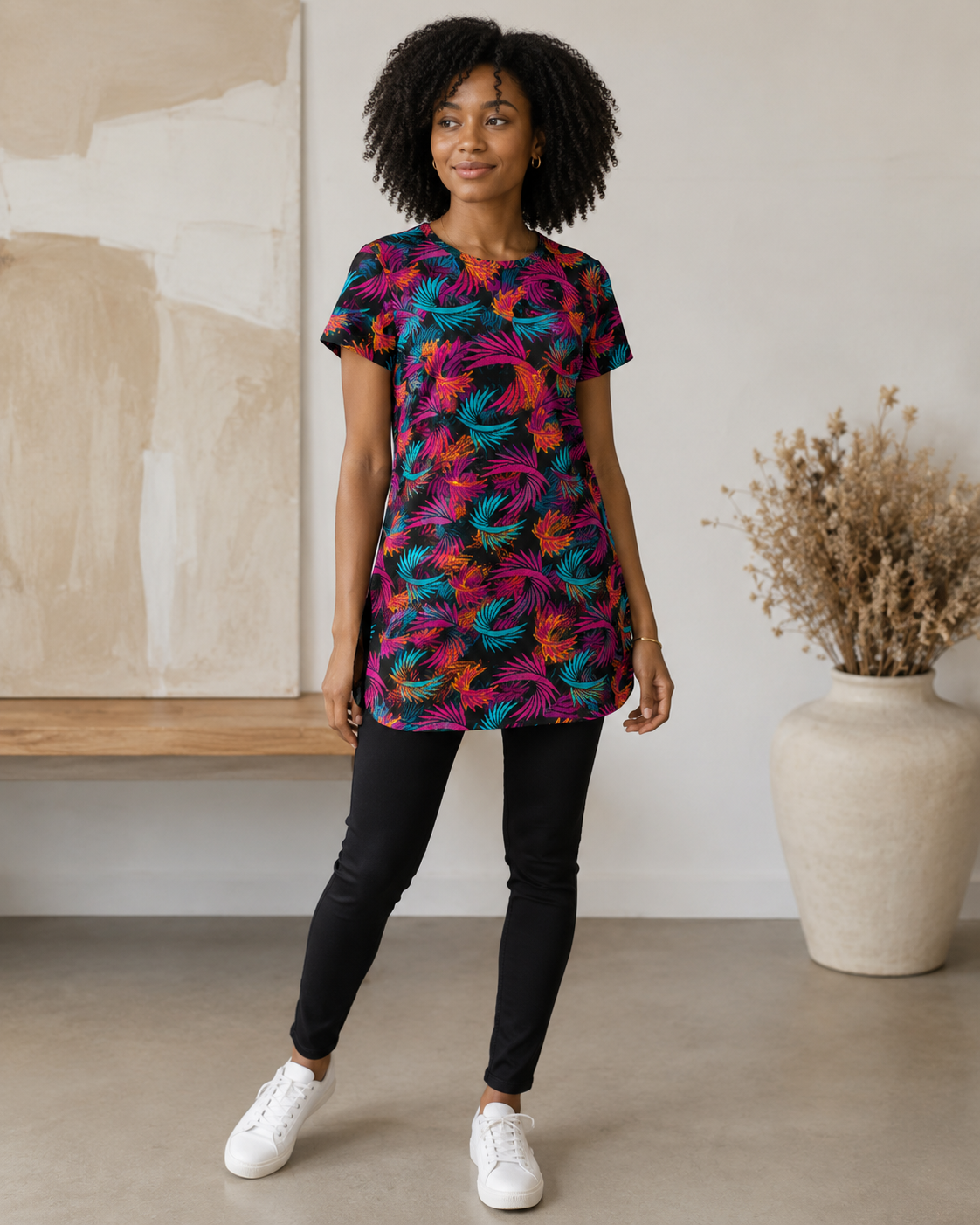 Person wearing a colorful patterned shirt standing in a room with a vase and abstract painting in the background.