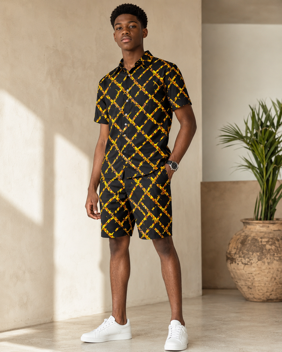 Man wearing a black and yellow patterned outfit standing indoors with a plant in the background